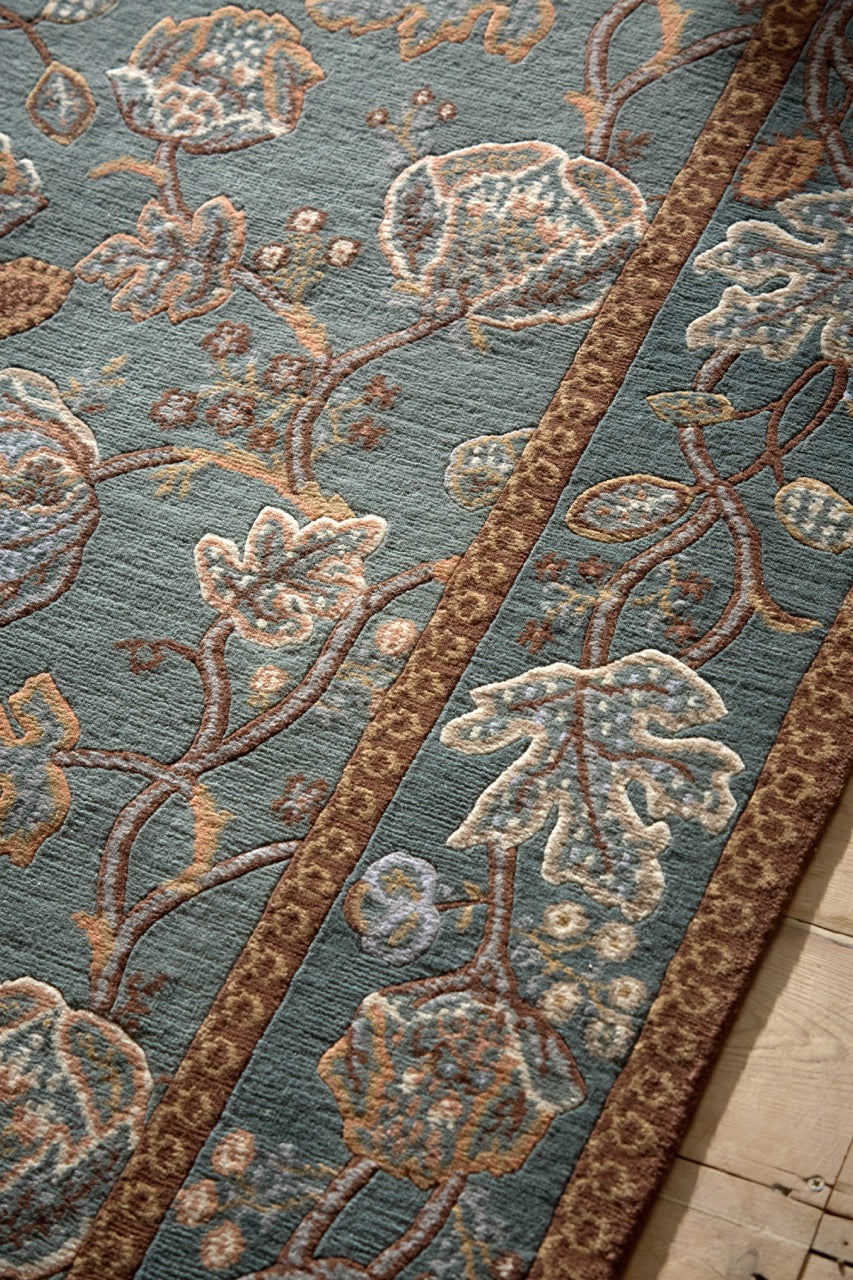 Morris & Co Theodosia Bottle Green rug in bottle green with caramel and ivory flowers, shown in an interior, third view
