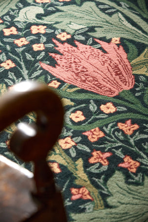 Morris & Co Lent Lily Indigo Madder rug in indigo with madder red tulips and sage leaves, shown in an interior, third view