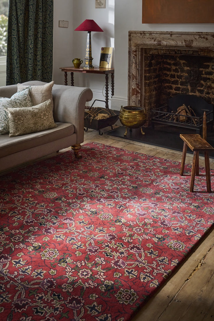 Morris & Co Persian Scroll Plum rug in warm red with cream, olive and aubergine, shown in an interior