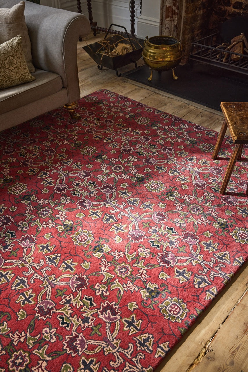 Morris & Co Persian Scroll Plum rug in warm red with cream, olive and aubergine, shown in an interior, second view