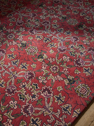 Morris & Co Persian Scroll Plum rug in warm red with cream, olive and aubergine, shown in an interior, third view
