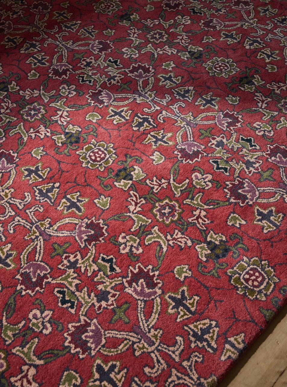 Morris & Co Persian Scroll Plum rug in warm red with cream, olive and aubergine, shown in an interior, third view