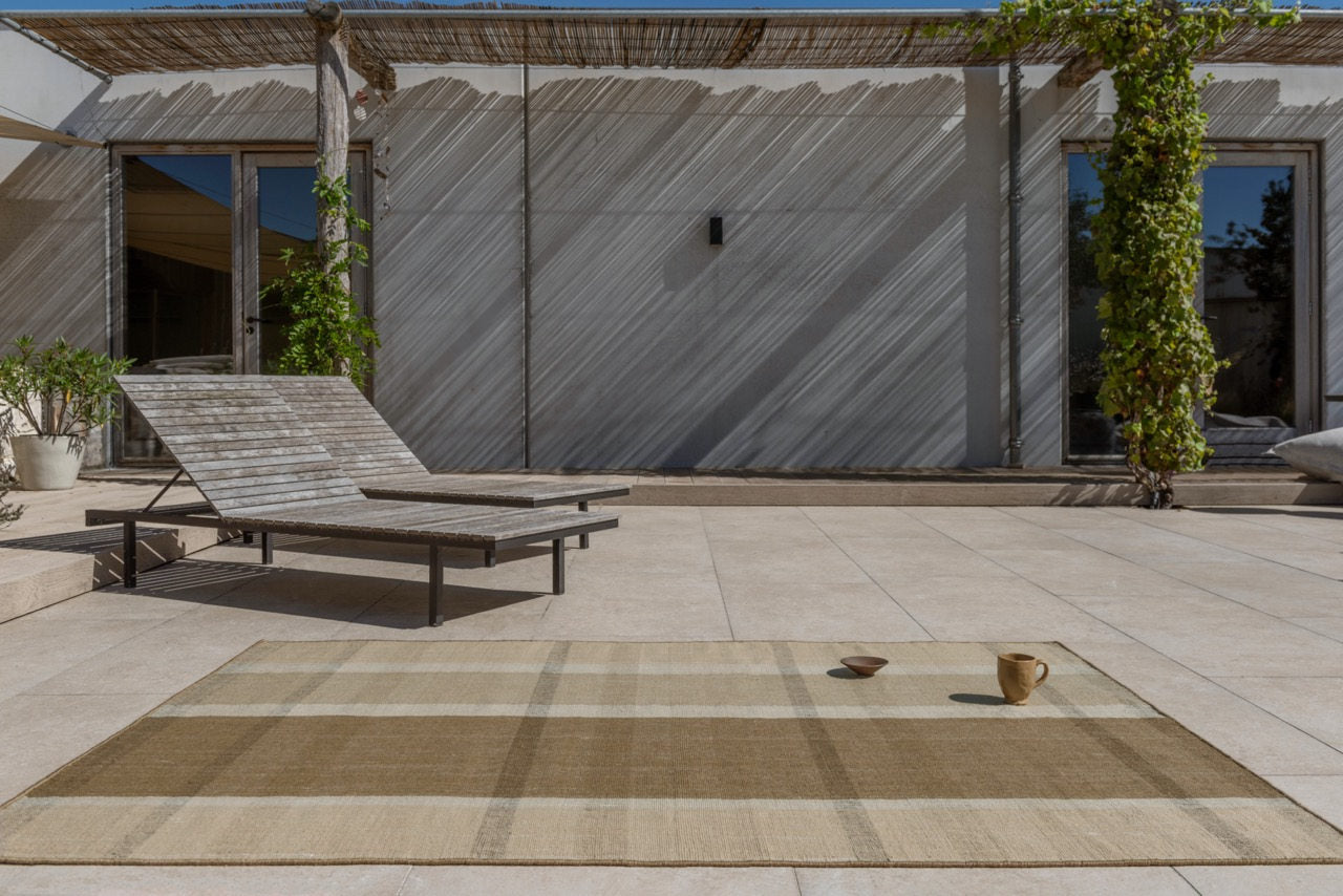 Exterior lounge featuring Zona Block Stripe Cashew rug with modern seating on tiled patio