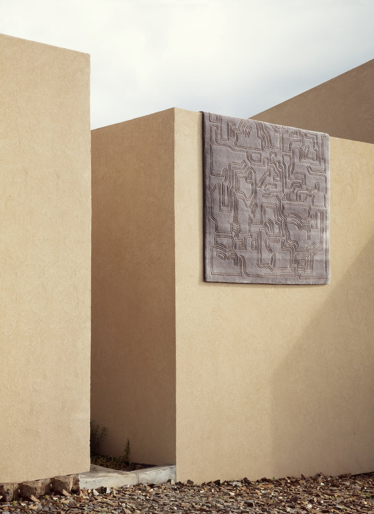 Massimo Structures 2.0 Volcano Dust rug, shown hanging on a sunlit outdoor wall